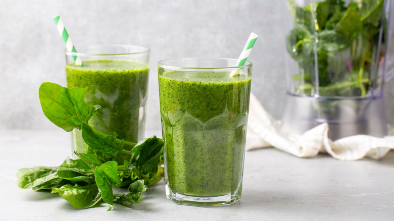 Two glasses of green smoothie with fresh salad leaves