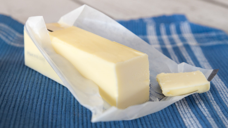 A stick of unwrapped butter on a blue cloth