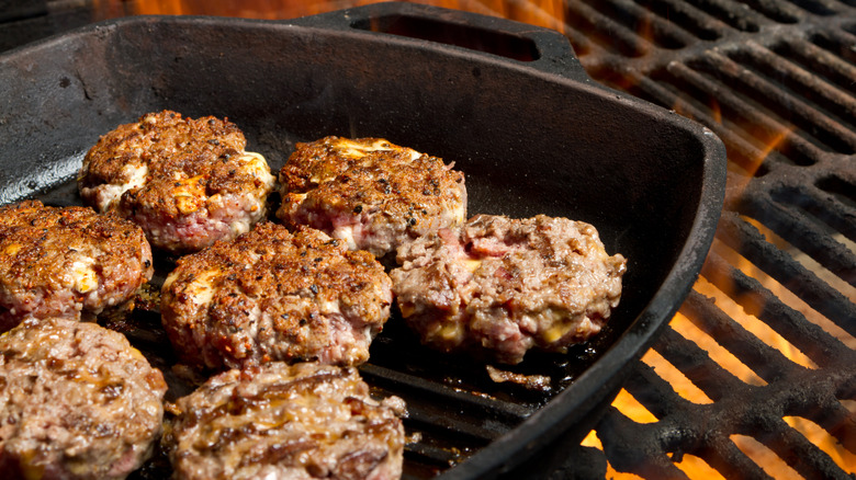 slider hamburger patties on a cast iron skillet