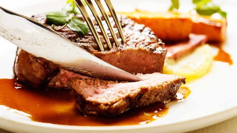 Fork and knife cutting through steak