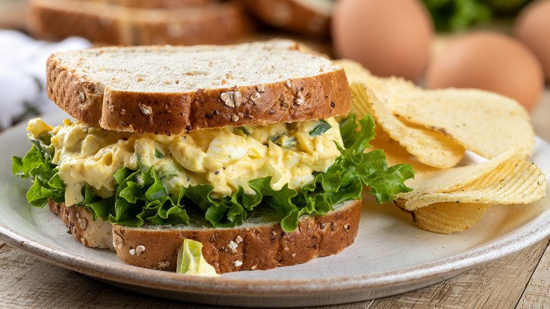 An egg salad and lettuce sandwich with a side of chips