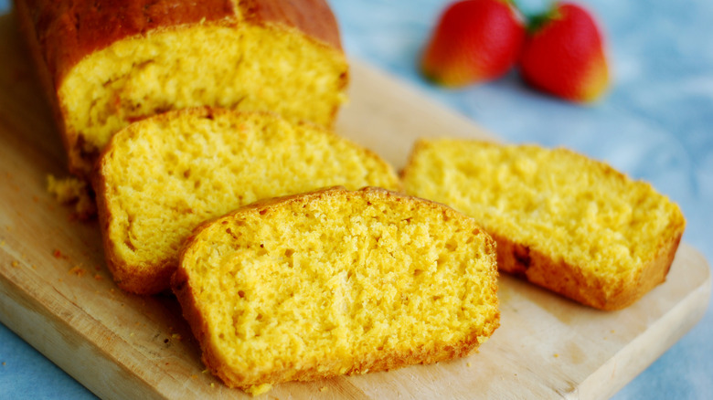 Close up of a loaf of pound cake sitting next to strawberries