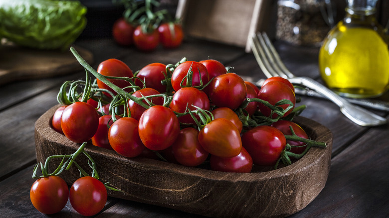 Cherry tomatoes on a wooden board with a jug of olive oil