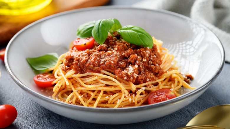 Bowl of spaghetti with bolognese, cherry tomatoes, and basil