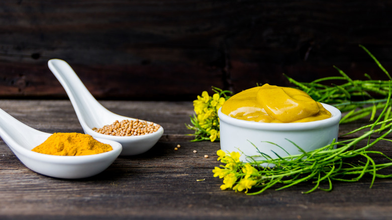 Mustard sauce, seeds, and powder on a wooden surface