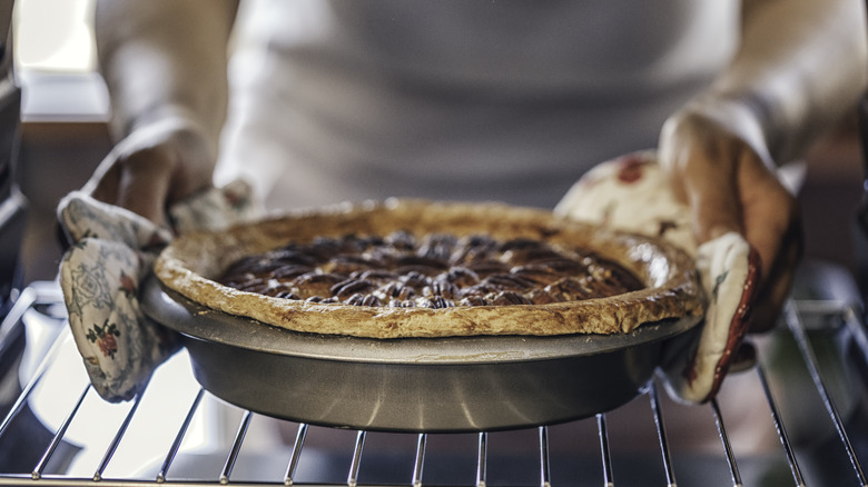 Someone placing a pecan pie into the oven