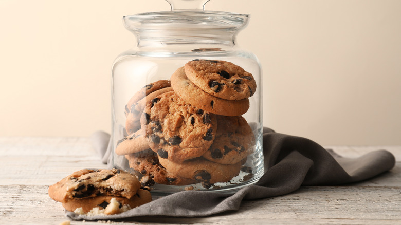 Glass container with freshly made chocolate chip cookies in it.