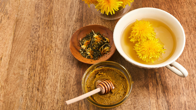 dandelion root tea with honey on a wooden table with yellow dandelions around