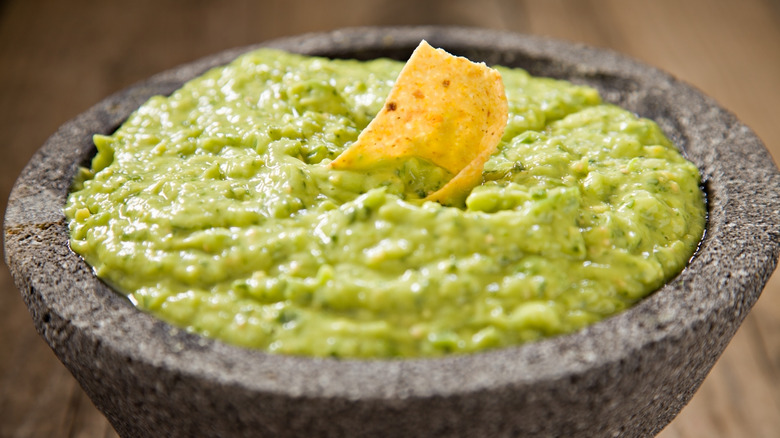 Creamy guacamole in a bowl with a tortilla chip