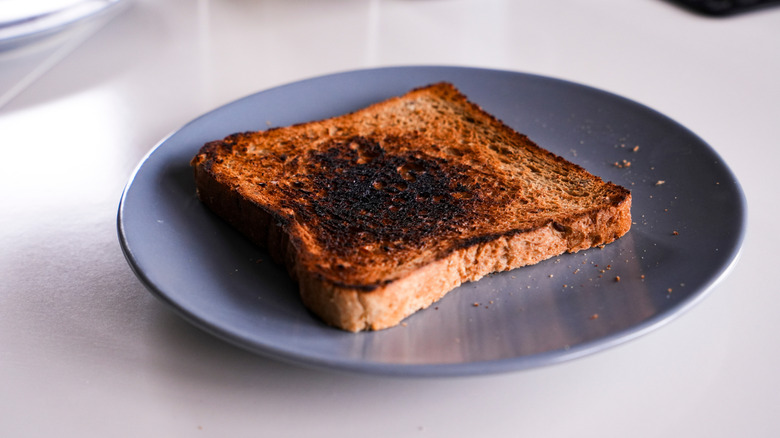 A burnt piece of toast sitting on a plate.