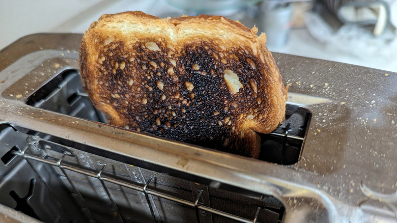 A piece of burnt toast in a toaster.