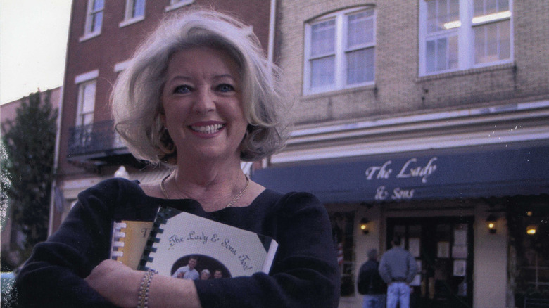 Paula Deen carrying cookbooks in front of restaurant