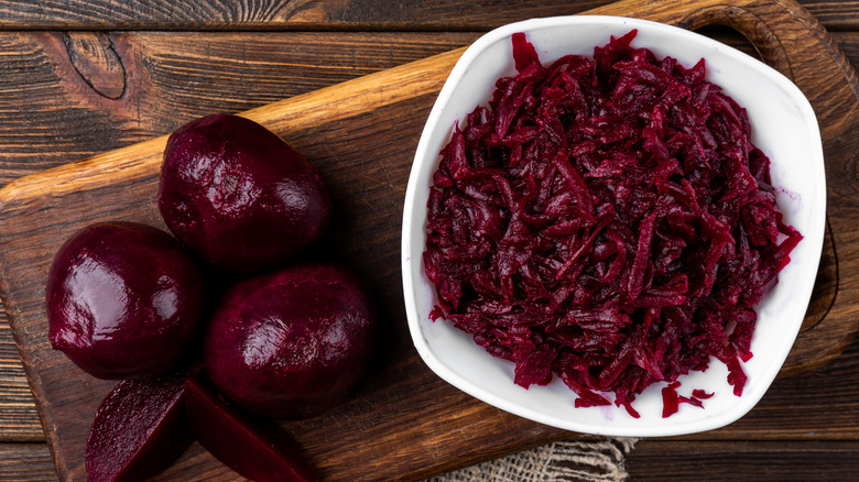 grated beetroot and whole beetroot on wooden board