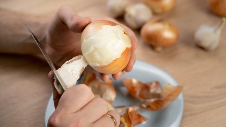 Hands peeling an onion