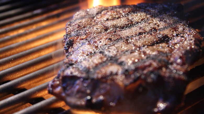 A ribeye steak cooking on a grill