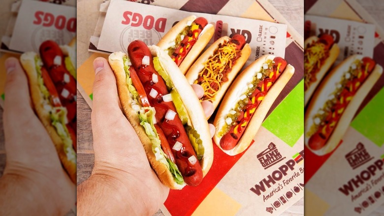 A hand holds a Whopper Dog, hovering other hot dogs below