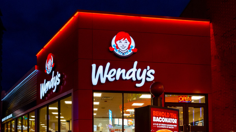 The exterior of a Wendy's location with red overhead lights on at night