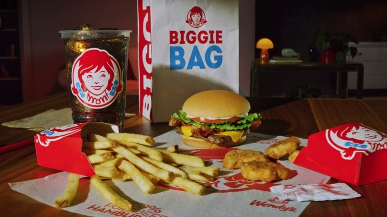 Each of the items included in Wendy's Biggie Bag on display in a dark dining room.