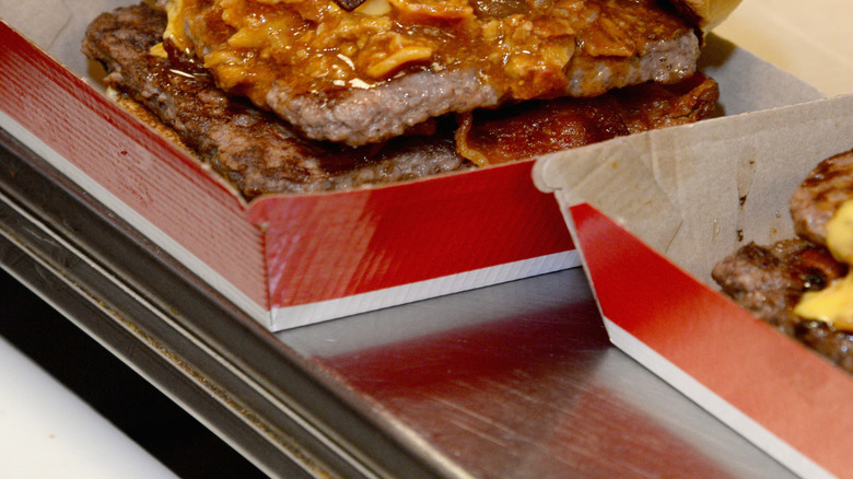 A Wendy's baconator cheeseburger with chili on it in a cardboard box.