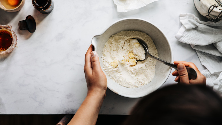 A person stirring butter into cake mix