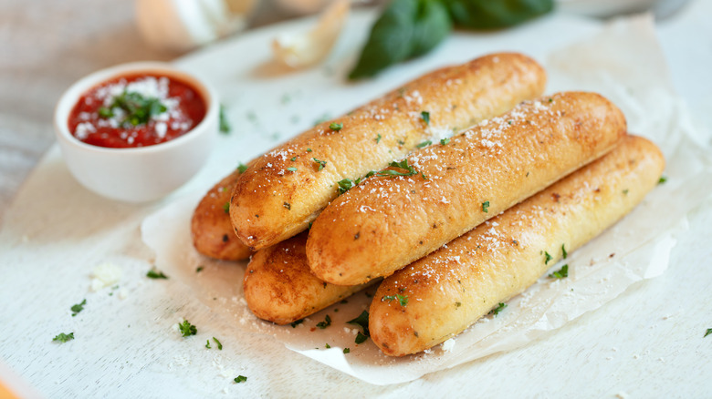 Breadsticks with herbs and parmesan on top and a side of marinara sauce