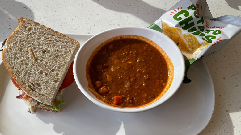 A bowl of soup, a sandwich, and a bag of chips served on a plate at Panera Bread