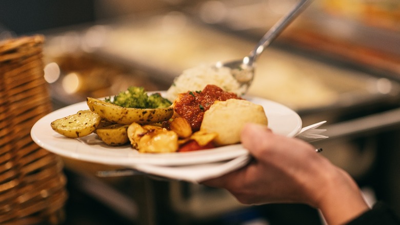 person spooning food onto plate