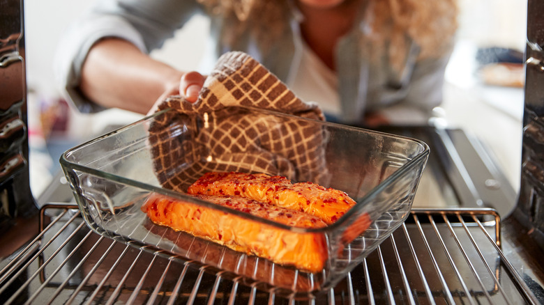 Woman removing salmon from oven