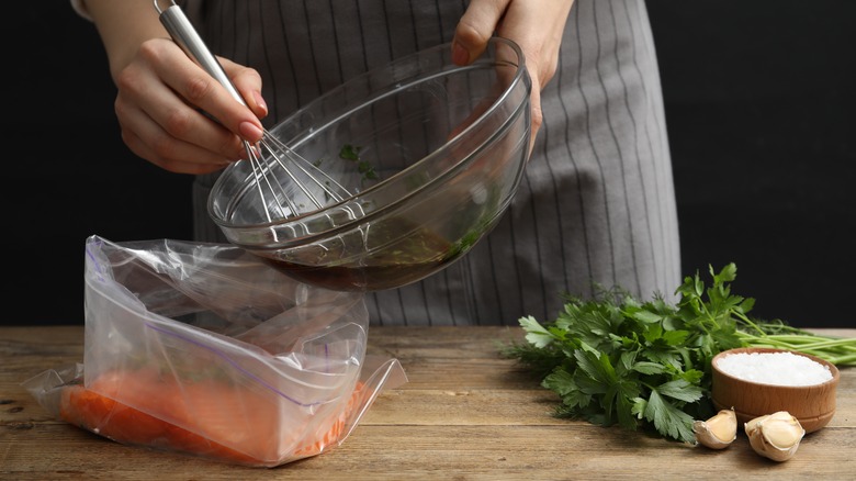 Woman's hands pouring a marinade into a bag of salmon.