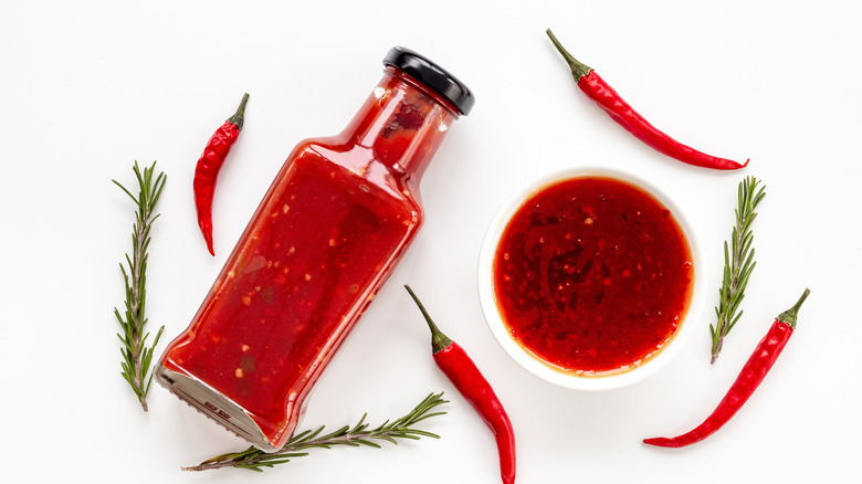 A bottle of hot sauce with red chilis surrounding it