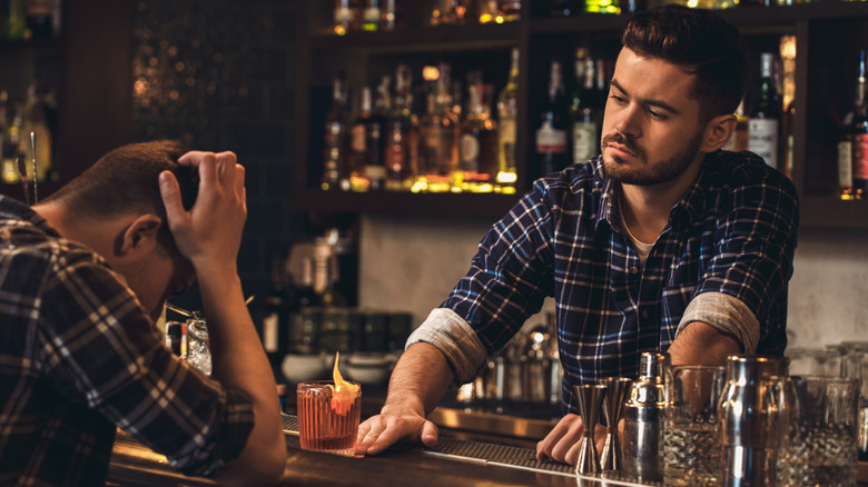 Young bartender looks at disappointed customer