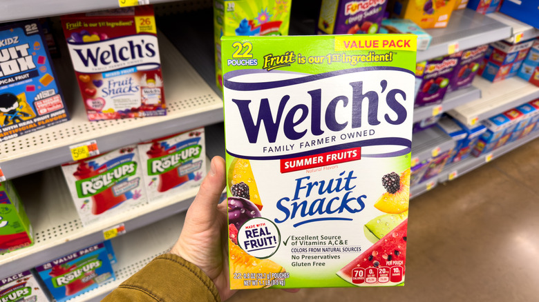 A person holding a box of Welch's Fruit Snacks in a grocery store