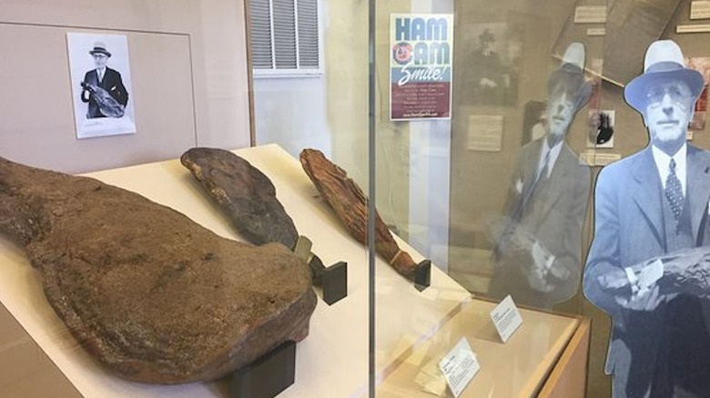 A glass case display containing hams next to a cut out of a historical figure