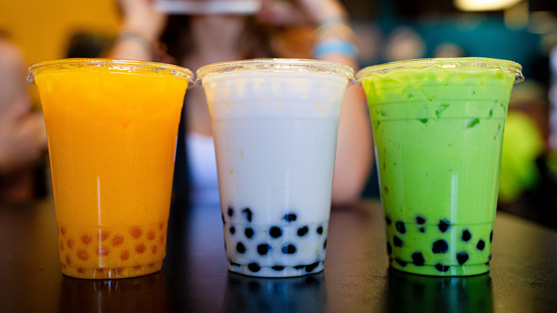 Three boba drinks, from left to right in mango, coconut, and matcha flavors