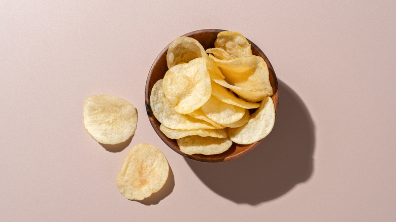 Potato chips piled in a brown bowl.