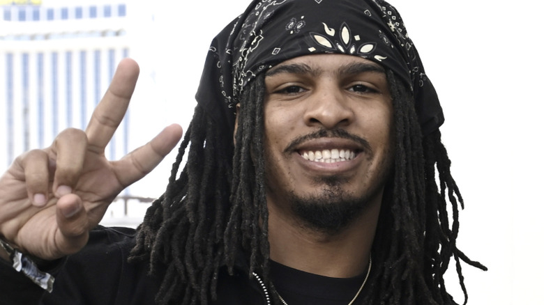 Food reviewer Keith Lee smiles and holds up a peace sign with his hand