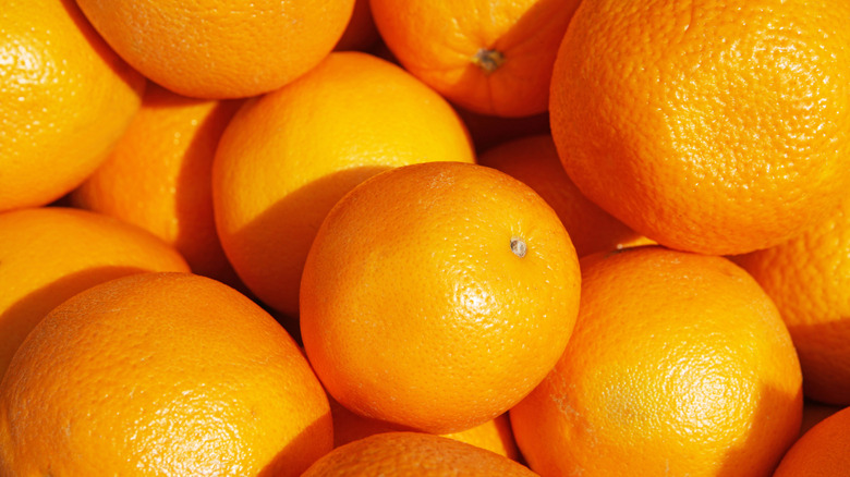 A pile of fresh oranges with the peel on