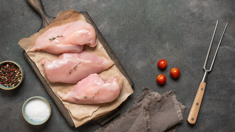 raw chicken breasts on wooden board