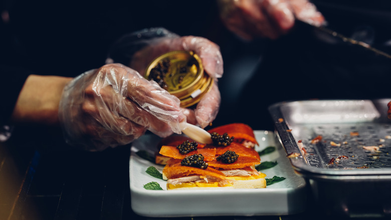 Chef topping fish with caviar