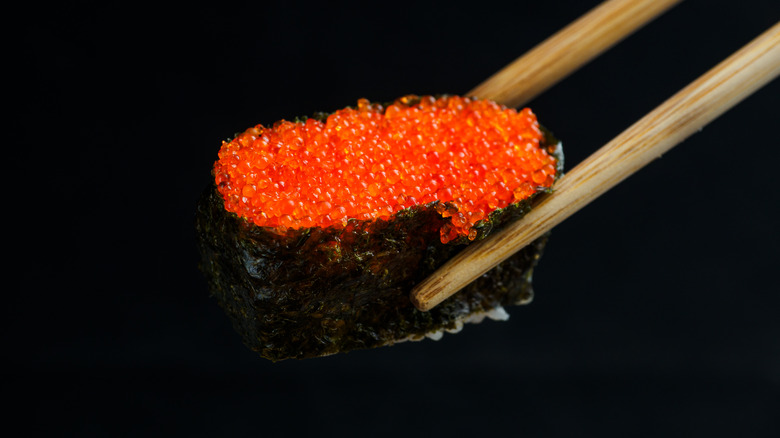 tobiko on sushi roll black background