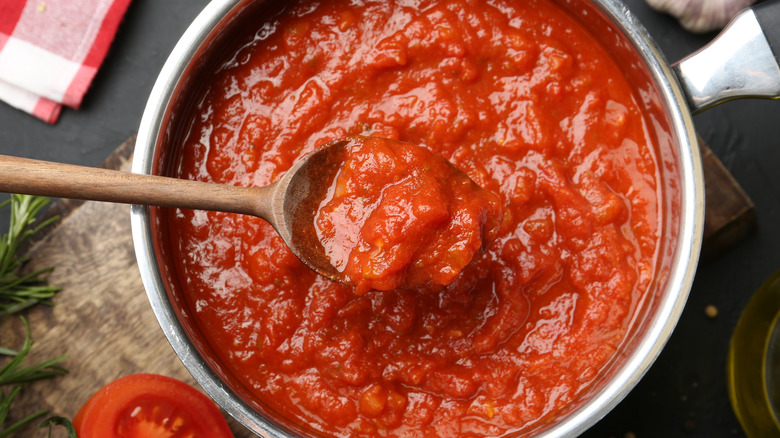 Top view of tomato sauce in pot with wooden spoon