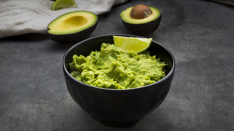 bowl of guacamole surrounded by fresh produce