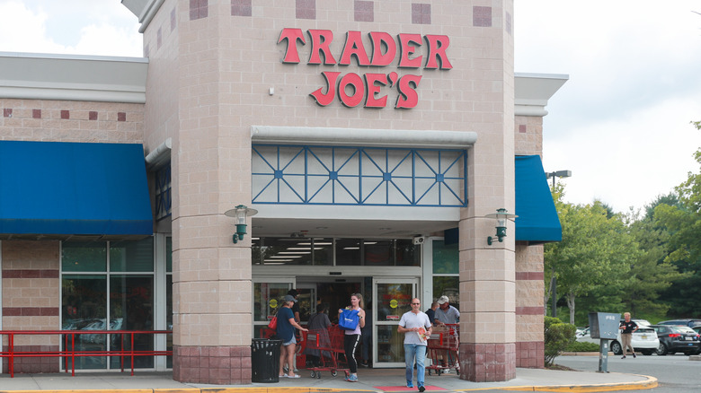 The exterior of a Trader Joe's during the day with customers walking in and out of the grocery store.