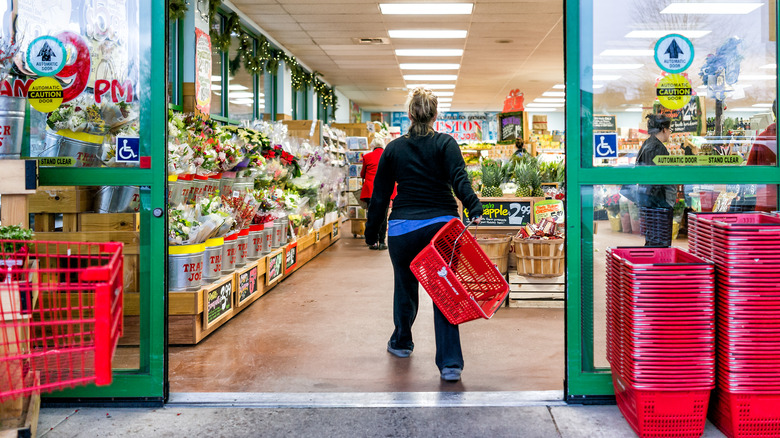 Woman entering Trader Joe's store holding red basket