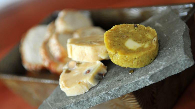 Round slices of compound butter on an angled stone slab