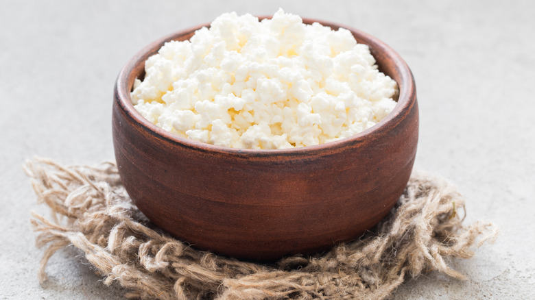 Cottage cheese in a wooden bowl on some twine fabric.