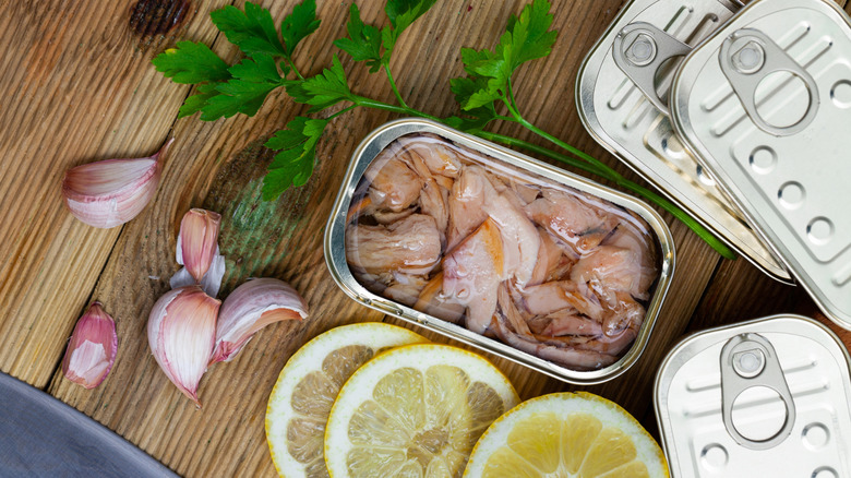 open can of tuna next to garlic, lemon, and parsley