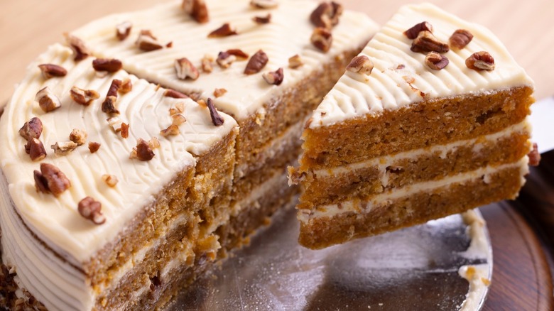 A whole carrot cake with a slice taken.