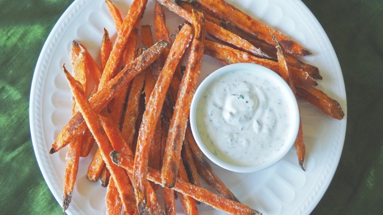 Plate of crunchy sweet potato fries and creamy herb dip.