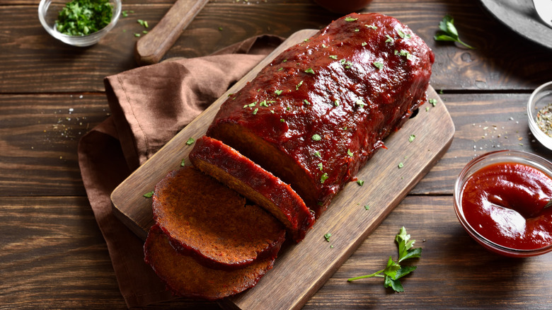 Meatloaf with sauce on a wooden platter